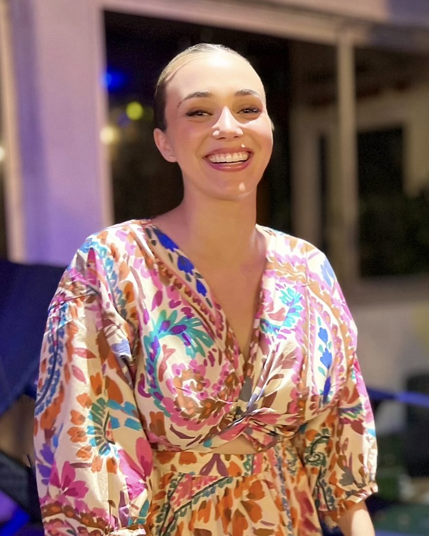 Charlotte Bard, souriante, en robe à motifs colorés, un soir
